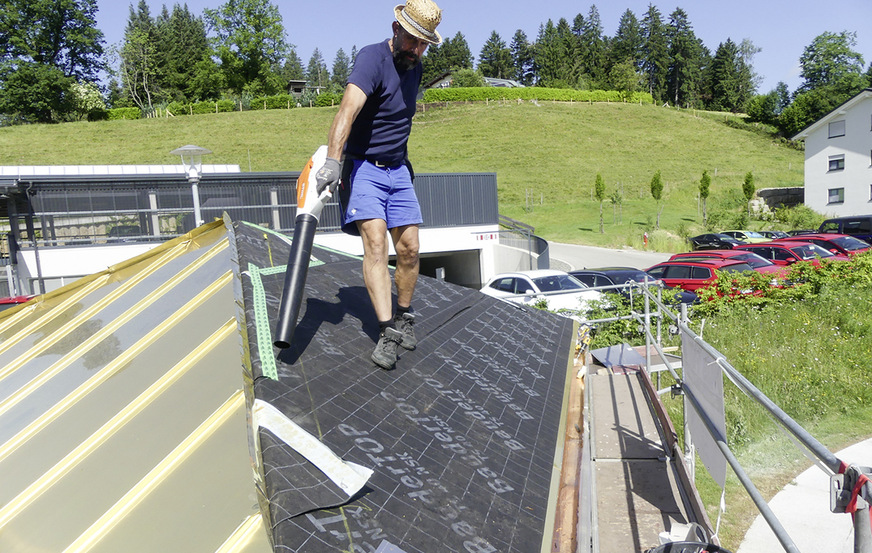 Alexander Rigal befreit die Dachfläche von Verunreinigungen. Die Falzeinführung am Grat erfolgte analog zur Traufe stehend und rund ausgeschweift