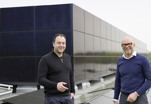  Die „Pro+“-Geschäftsführer Michael Jung und Ingo Gramm vor einer mit PV-Modulen bekleideten „Pro+“-Fassade - © Bild: BAUMETALL
