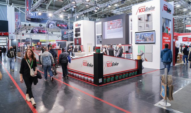 Alt-Text: „Messestand mit Besuchern, die sich über ‚100 Jahre Enke‘ informieren, umgeben von Bau- und Bedachungsmaterialien, innovativen Verarbeitungstechniken und modernen Werkzeugpräsentationen für Spengler-, Klempner- und Dachdeckerbetriebe. - © Bild: BAUMETALL