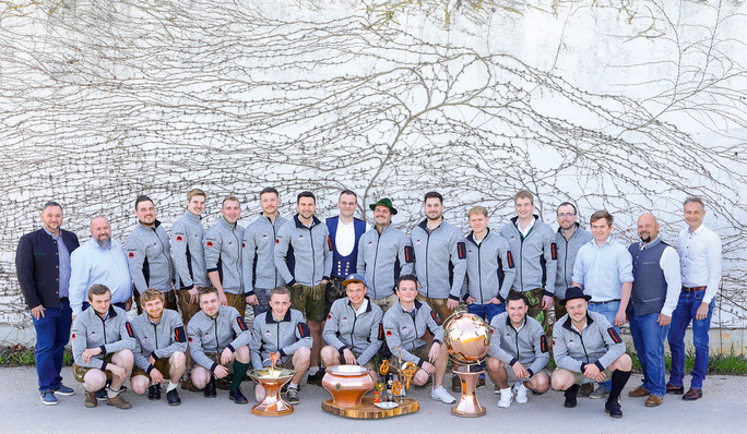 Eine Sportmannschaft posiert im Freien in passenden Jacken mit mehreren großen Trophäen, die vor ihnen ausgestellt sind. - © Bild: Fotostudio Hackl für HWK N-O