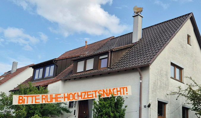Weißes Haus mit einem Transparent mit der Aufschrift "BITTE RUHE-HOCHZEITSNACHT" an der Fassade. - © Bild: Eisenhard